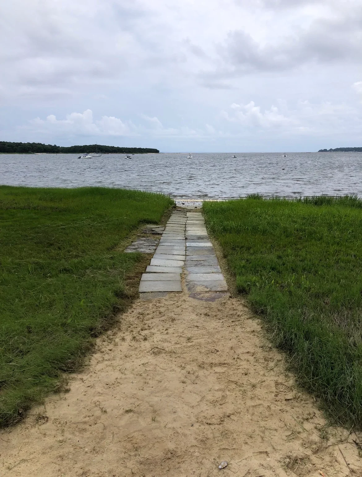 Wooden boardwalk pathway through marsh grass leading to waterfront